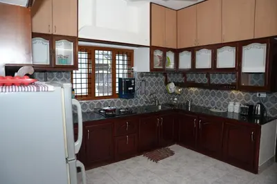 a kitchen with wooden cabinets and a white refrigerator at White Haven in Angamali