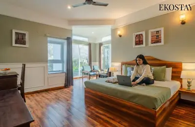 a woman sitting on a bed with a laptop at EKOSTAY - Echo Villa in Kodaikānāl