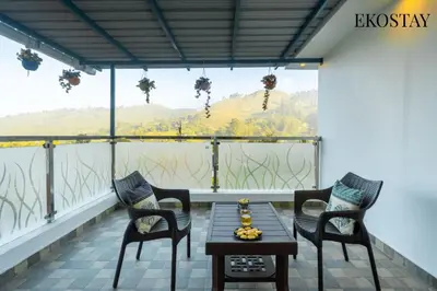 a balcony with two chairs and a table and a view at EKOSTAY - Echo Villa in Kodaikānāl