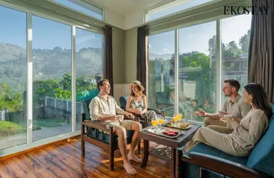 a group of people sitting in a room with large windows at EKOSTAY - Echo Villa in Kodaikānāl