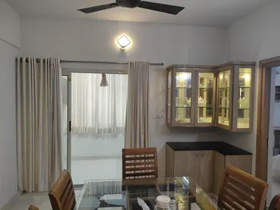 a dining room with a glass table and a ceiling fan at Aapt green field in Trichūr