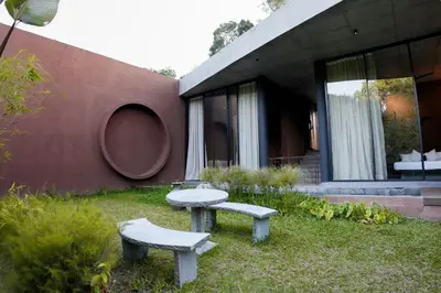 a house with two benches in the grass next to a building at Ayana Villa By KPM in Varagampadi