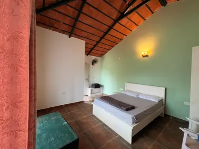 a bedroom with a white bed and a wooden ceiling at Paddy Creek Jungle Resort Coorg in Virajpet