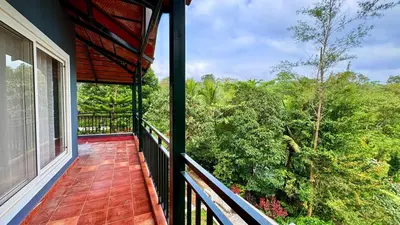 a balcony of a house with a view of trees at Paddy Creek Jungle Resort Coorg in Virajpet