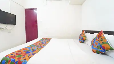 a bedroom with a white bed with colorful pillows at H N Residency in Coimbatore