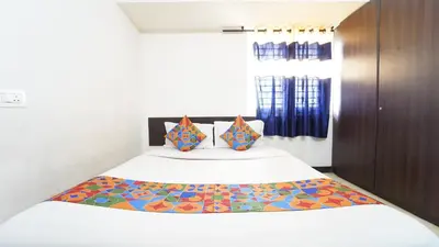 a bedroom with a large white bed with colorful pillows at H N Residency in Coimbatore