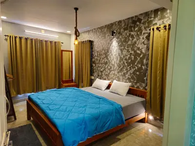 a bedroom with a bed with a blue comforter at Vista Chembra Service Apartment 20B in Meppādi