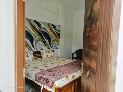 a bedroom with a bed and a wooden door at Darby Homestay in Kanthalloor
