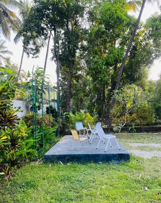two chairs and a table on a blue board in the grass at HARSHAM Eco Village in Puthuppādi