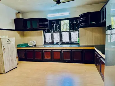 a kitchen with black cabinets and a counter top at HARSHAM Eco Village in Puthuppādi