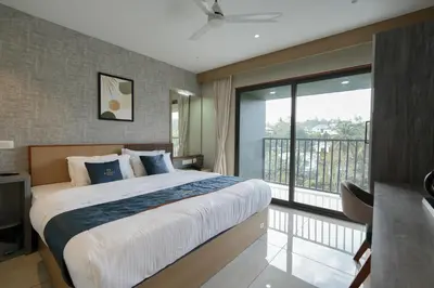 a bedroom with a large bed and a balcony at Rasha Suites in Kalpetta