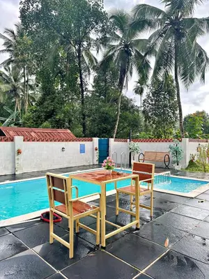 a wooden table and two chairs next to a pool at Bougainvilla in Kozhikode