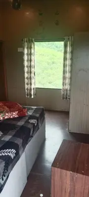 a small room with a bed and a window at Bison valley in Ooty