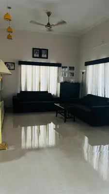 a living room with two black couches and a ceiling at Parthipuram in Thottada