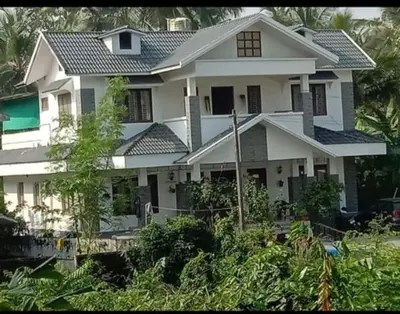 a large white house with a lot of plants at Parthipuram in Thottada