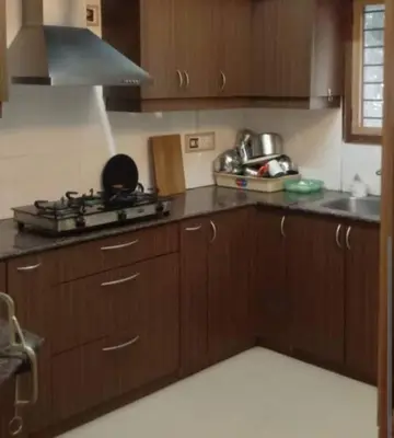 a kitchen with wooden cabinets and a stove top oven at Puthooram Veedu in Kannur