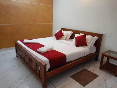 a wooden bed with red and white pillows on it at Valley De Hills Villa Room in Attappādi