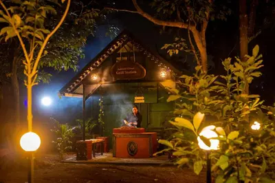 a woman sitting in front of a house at night at Lakkidi village resort wayanad in Vythiri