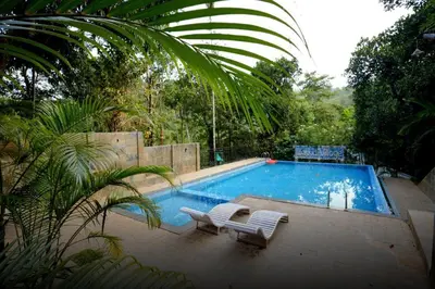a swimming pool with two lounge chairs next to it at Lakkidi village resort wayanad in Vythiri