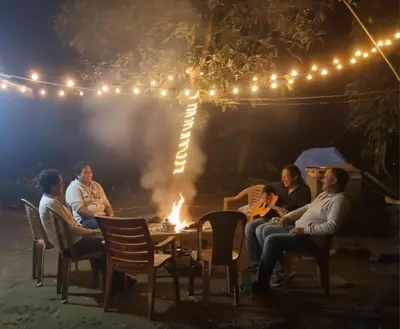 a group of people sitting around a fire at night at Riverside Homestay Mankulam in Viripara