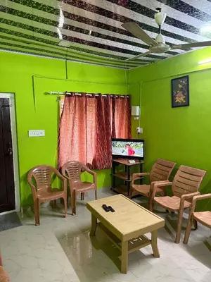 a living room with green walls and a table and chairs at Riverside Homestay Mankulam in Viripara