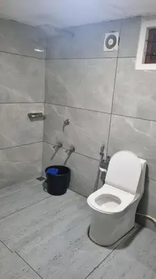 a bathroom with a white toilet in a stall at Riverside Homestay Mankulam in Viripara