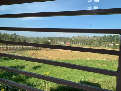 a view through the blinds of a window of a field at Elysian in Mananthavady