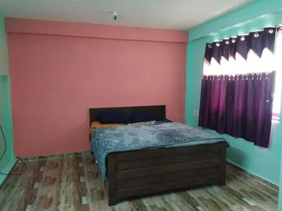 a bedroom with a bed and a red wall at Nira Homestay in Kodaikānāl