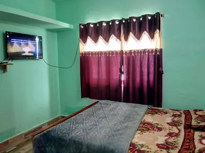 a bedroom with a bed and a tv and a window at Nira Homestay in Kodaikānāl