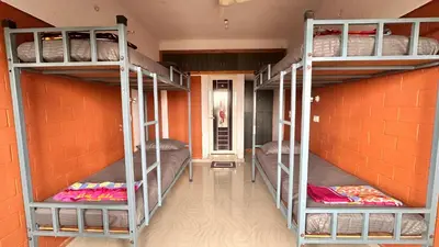 two bunk beds in a room with an orange wall at Campside Stays in Nāganahalli