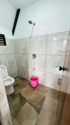 a bathroom with a toilet and a pink bucket at Kacchi Kombu Castle By Calpavruksha Estate in Madikeri