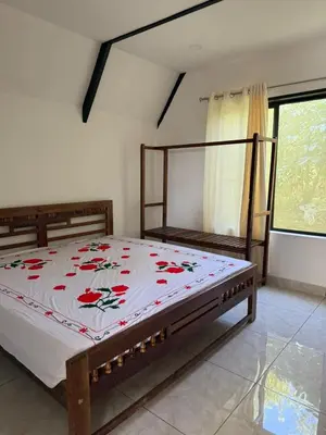 a bedroom with a bed with a flowered blanket on it at Kacchi Kombu Castle By Calpavruksha Estate in Madikeri