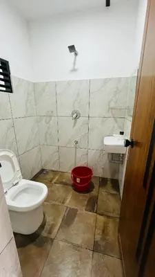 a bathroom with a toilet and a red bucket at Kacchi Kombu Castle By Calpavruksha Estate in Madikeri