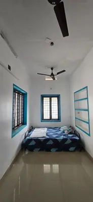 a bedroom with a bed in a room with two windows at JJ's Farmhouse in Thanniyam