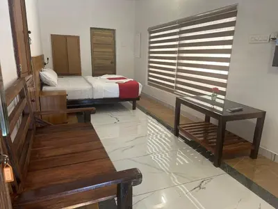 a bedroom with a bed and a table and a window at Vayuvana Heritage Organic Farm Resort in Panamaram