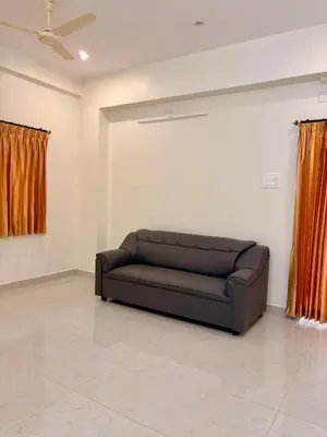 a black couch in a room with orange curtains at Nexus Living in Coimbatore