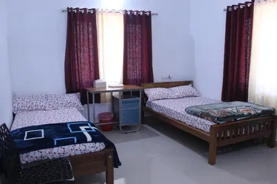 a bedroom with two beds and a desk and curtains at Orchid Homestay in Viripara