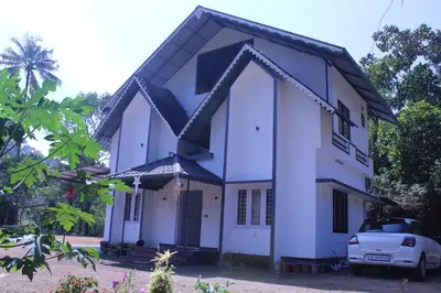a white house with a car parked in front at Orchid Homestay in Viripara