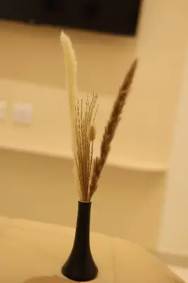 a black vase with some tall grass in it at Nilgiri Breeze Apartment in Pīlamedu