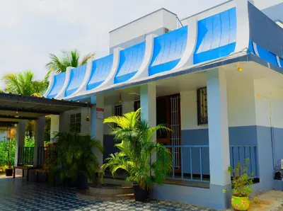 a blue and white building with palm trees in front at BGF Residency - Cottage in Coimbatore