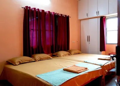 a bedroom with a large bed with red curtains at BGF Residency - Cottage in Coimbatore