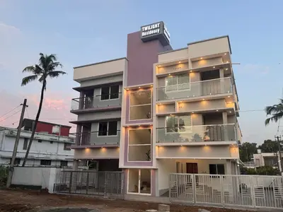 a tall building with balconies and a palm tree at Twilight Residency in Kizhake Chālakudi