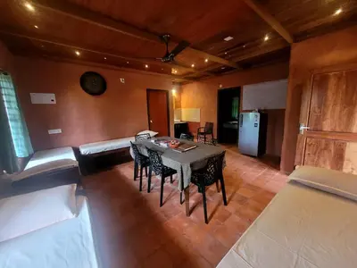 a dining room with a table and chairs and a kitchen at Dream Acres Mudhouse in Vallikavungal