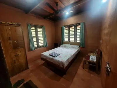 a bedroom with a bed and two windows at Dream Acres Mudhouse in Vallikavungal