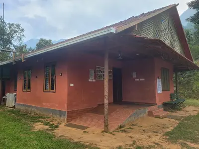 a small red house with a pole in front of it at Dream Acres Mudhouse in Vallikavungal