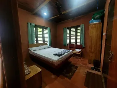 a bedroom with a bed and two windows at Dream Acres Mudhouse in Vallikavungal