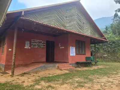 a red building with a bench in front of it at Dream Acres Mudhouse in Vallikavungal