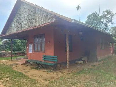 a small house with a green bench in front of it at Dream Acres Mudhouse in Vallikavungal