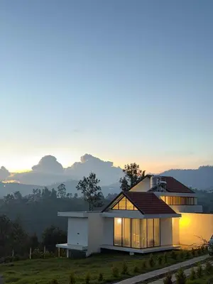 a house on a hill with the sunset in the background at Ozone The Misty Villa ooty ,Three Bed Room Luxury Private Jacuzzi Villa in Ketti