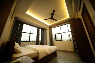 a bedroom with a ceiling fan and two windows at Spezio Luxurious Apartments in Perintalmanna